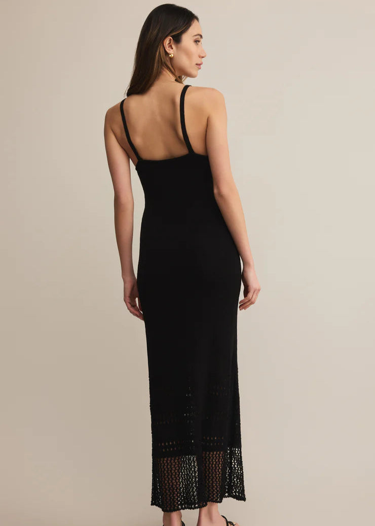 Woman wearing a black dress with lace details on a beige background