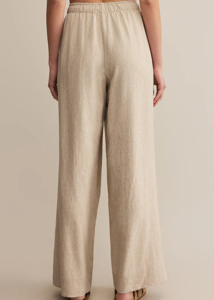 Beige linen pants worn by a person on a beige background
