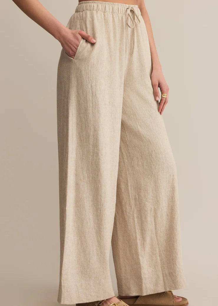 Beige linen pants worn by a person on a beige background