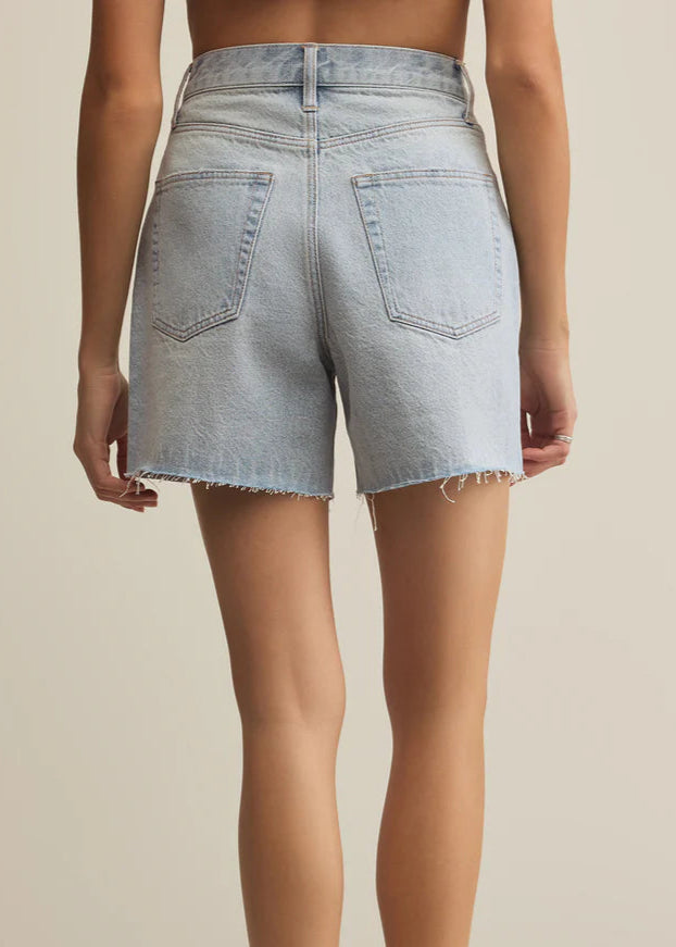 Light blue denim shorts worn by a person on a beige background