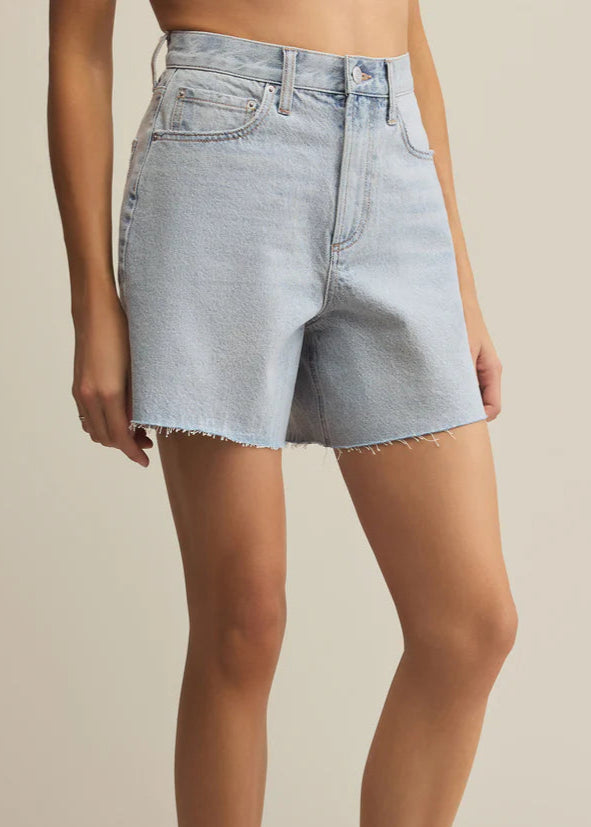 Light blue denim shorts worn by a person on a beige background