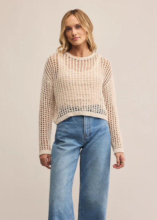 Woman wearing a beige knitted sweater and blue jeans on a beige background
