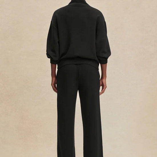 Person wearing a black outfit on a beige background