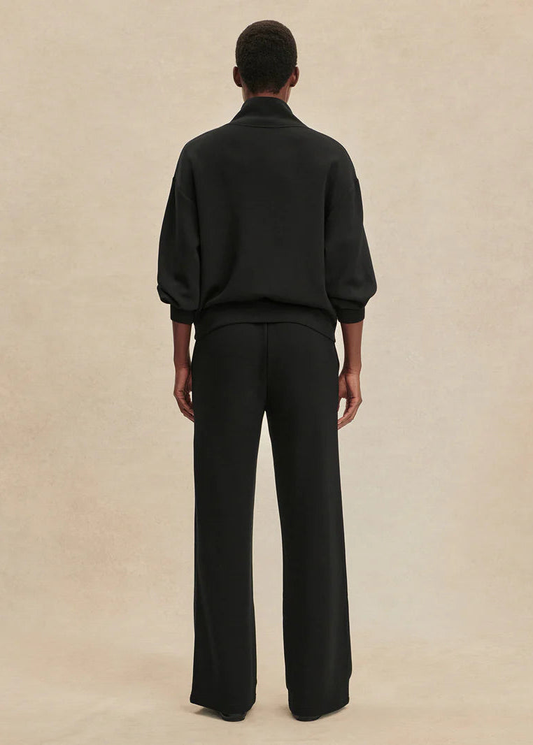 Person wearing a black outfit on a beige background