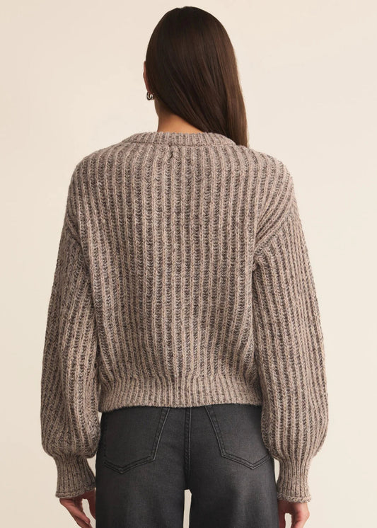 Person wearing a chunky knit sweater from behind on a beige background