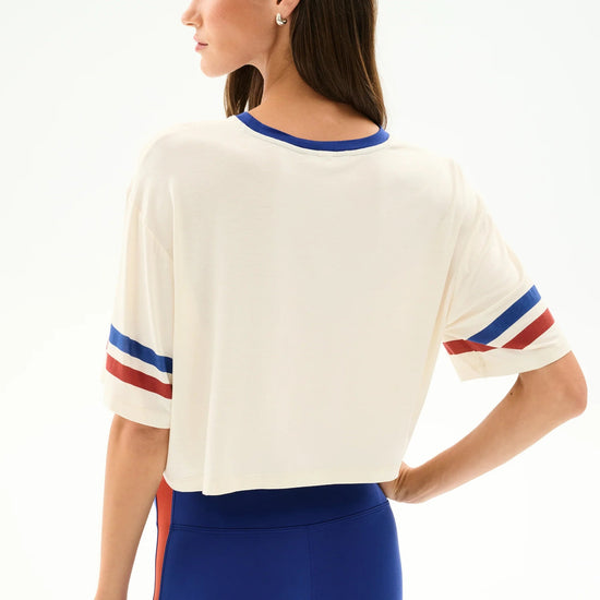 Women’s cream cropped tee with blue and red striped sleeves and royal blue high-waist leggings, at Ekam boutique Newport Beach