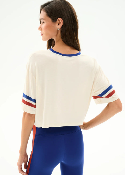 Women’s cream cropped tee with blue and red striped sleeves and royal blue high-waist leggings, at Ekam boutique Newport Beach
