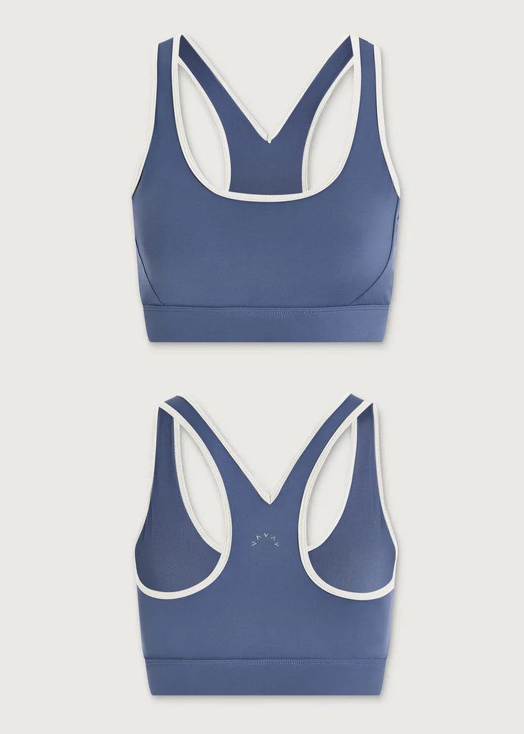 Two blue sports bras with white trim on a light gray background
