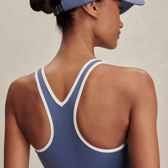 Person wearing a blue sports bra and cap on a neutral background