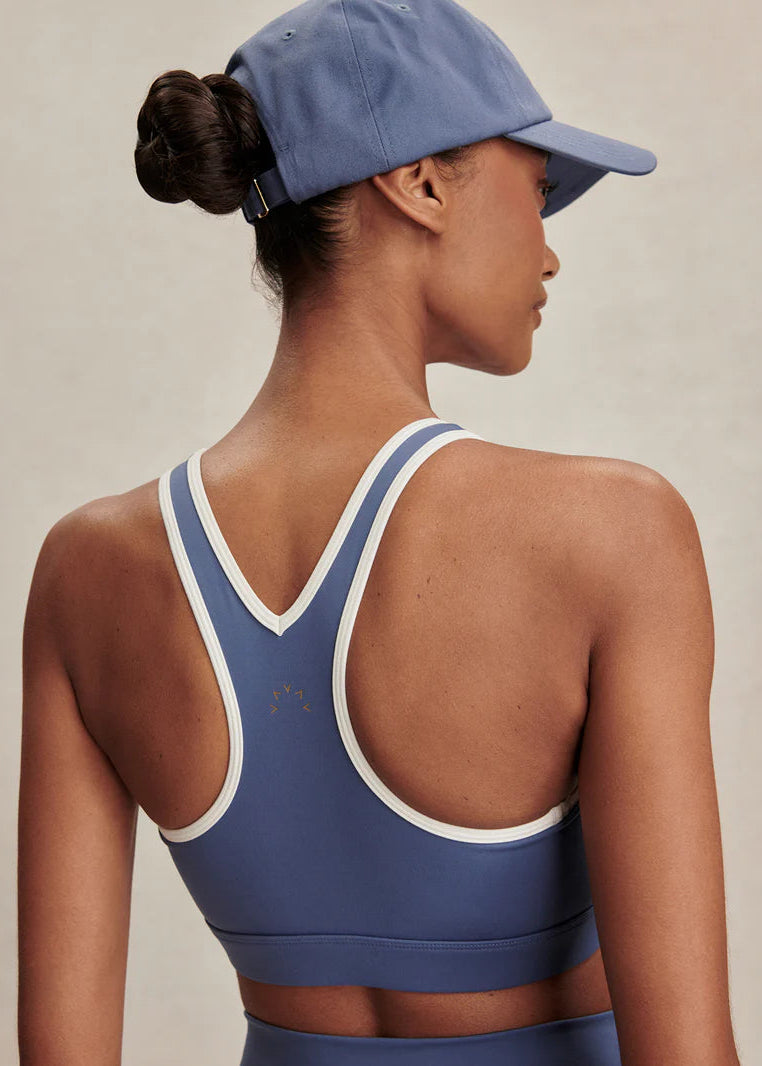 Person wearing a blue sports bra and cap on a neutral background