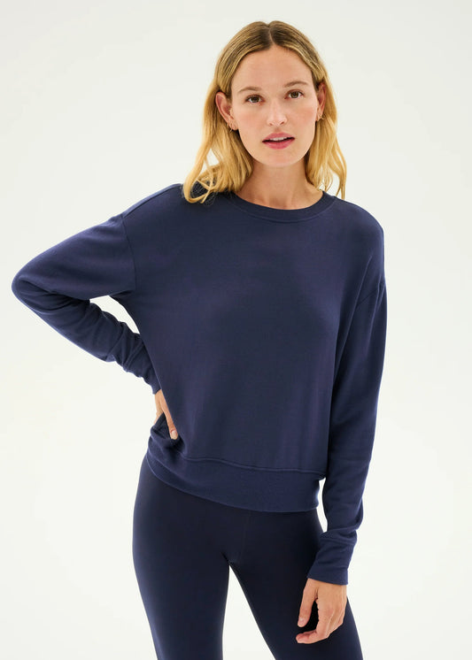 Woman wearing a navy blue sweatshirt and leggings on a white background