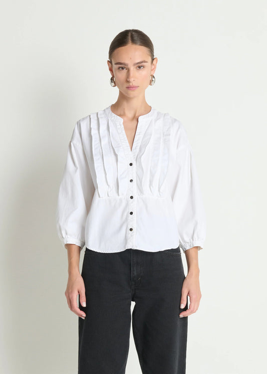 Person wearing a white blouse with black pants on a plain background