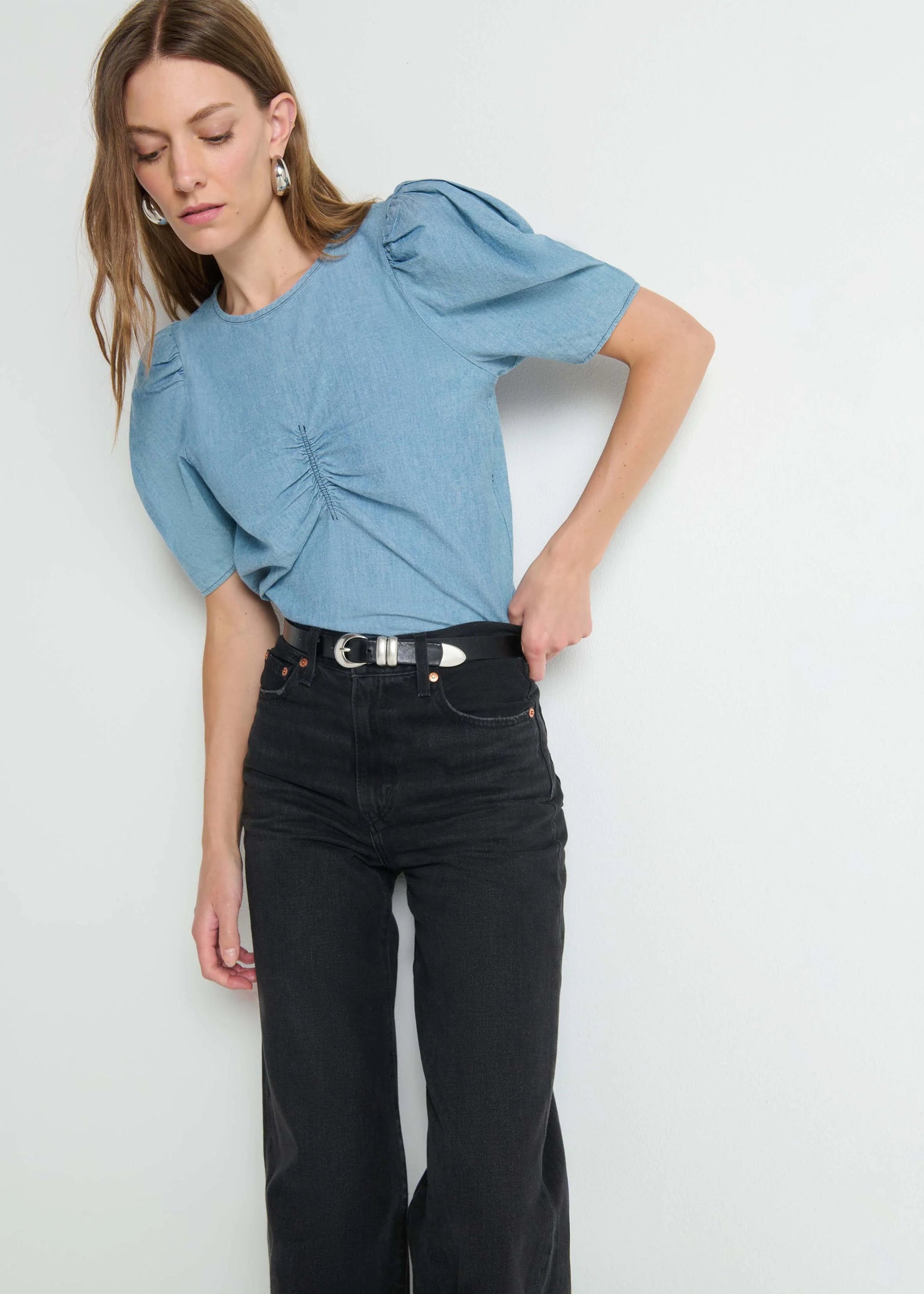 Woman wearing a blue top and black pants against a white background