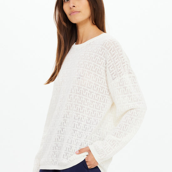 Woman wearing a white textured sweater on a white background