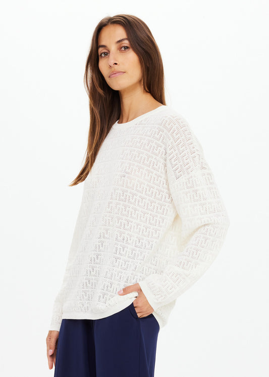 Woman wearing a white textured sweater on a white background