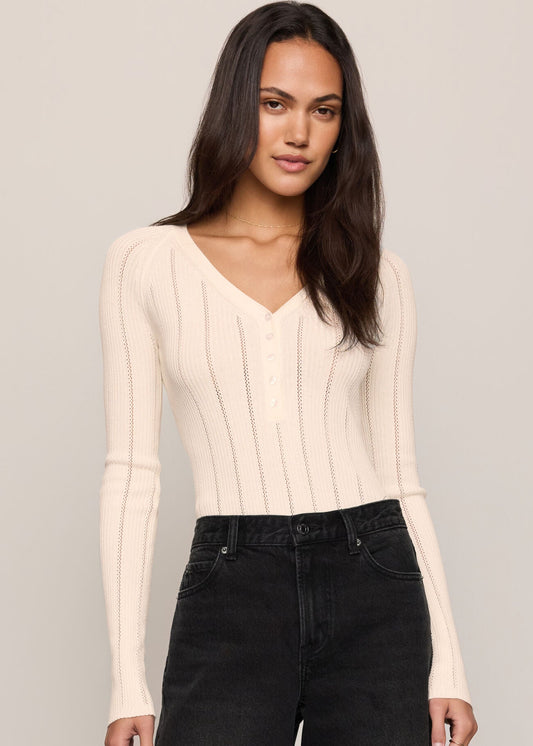 Women’s cream pointelle-knit V-neck henley sweater styled with black wide-leg jeans, available at Ekam boutique Newport Beach