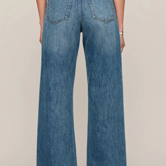 Back view of women’s medium-wash high-rise wide-leg jeans with patch pockets, available at Ekam boutique Newport Beach