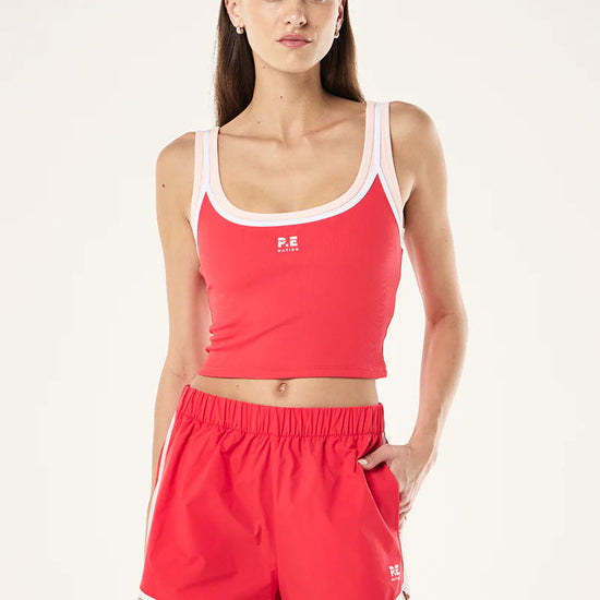 Woman wearing a red athletic outfit with a white logo on a light gray background