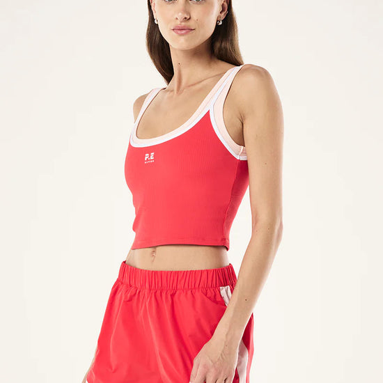 Woman wearing a red sports outfit with a white logo on a light gray background