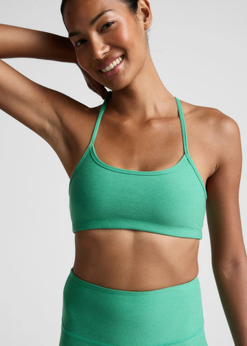 Woman wearing a green sports bra and leggings against a plain background