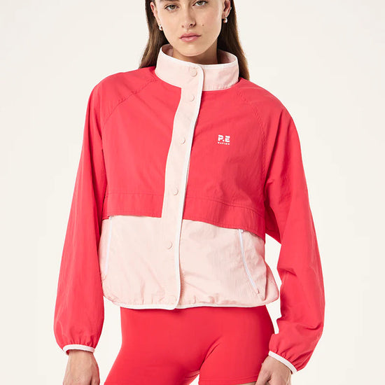 Woman wearing a red and pink jacket with a logo on a white background