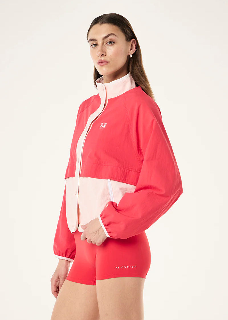 Woman wearing a red and white jacket with matching shorts on a white background