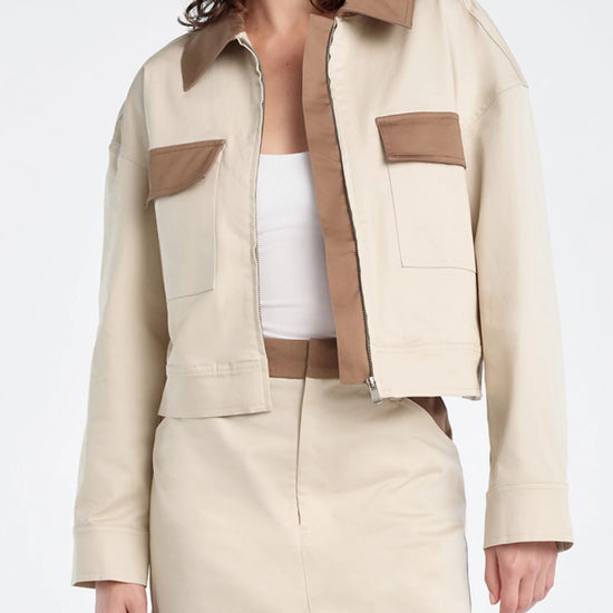 Woman wearing a beige and brown jacket with matching skirt on a white background