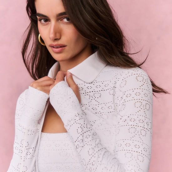 Woman wearing a white textured sweater against a pink background