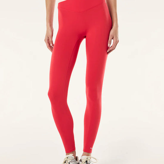 Person wearing red leggings and a red sports bra on a white background