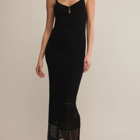 Woman wearing a black slip dress with lace hem on a beige background