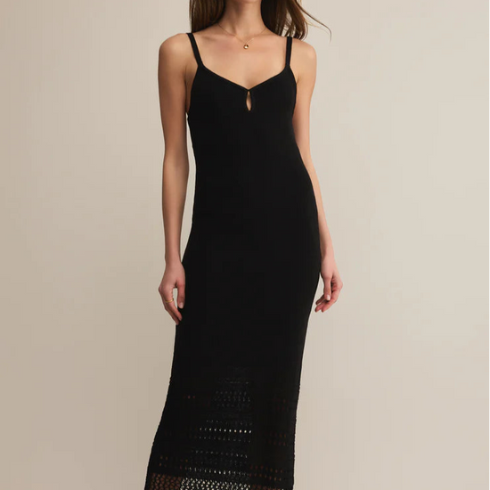 Woman wearing a black slip dress with lace details on a beige background