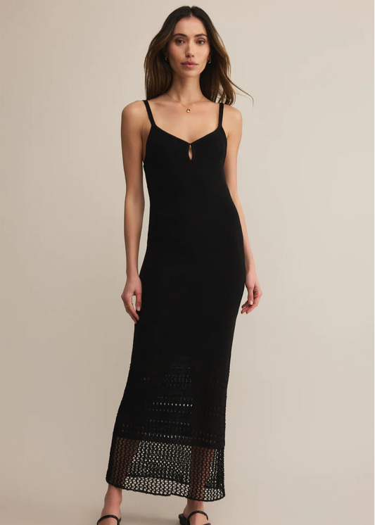 Woman wearing a black slip dress with lace details on a beige background