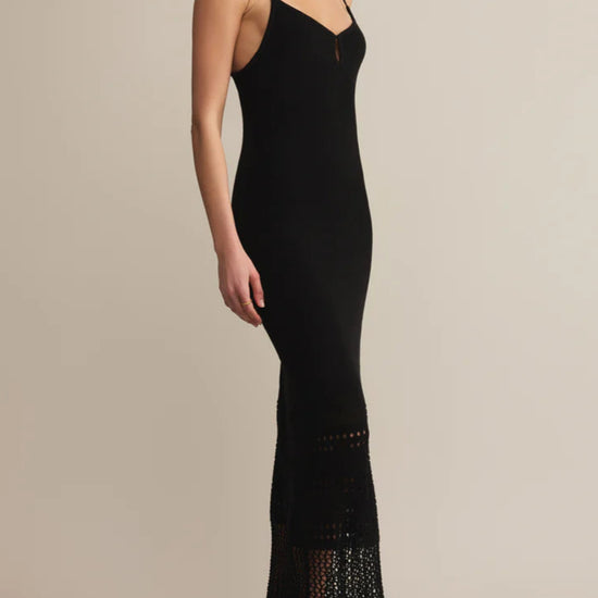 Woman wearing a black dress with lace details on a beige background