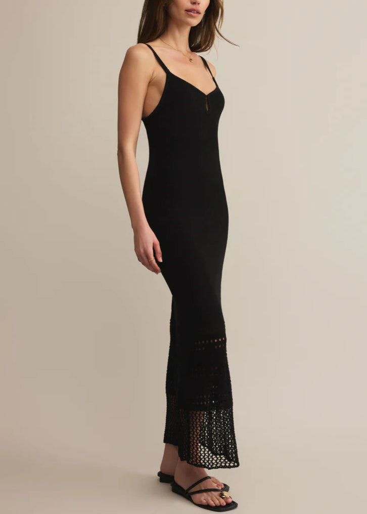 Woman wearing a black dress with lace details on a beige background