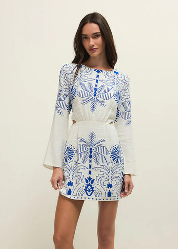 Woman wearing a white dress with blue floral patterns on a plain background