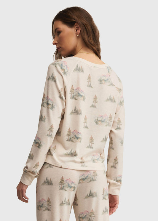 Woman wearing a cream-colored pajama set with nature-themed print on a plain background