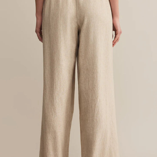 Beige linen pants worn by a person on a beige background