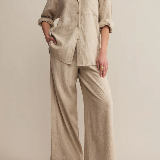Woman wearing a beige linen outfit on a plain background