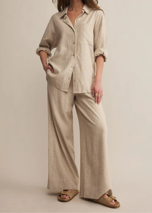Woman wearing a beige linen outfit on a plain background