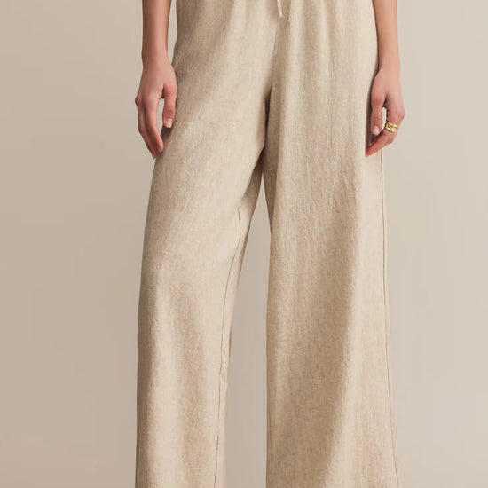 Beige linen pants worn by a person on a beige background