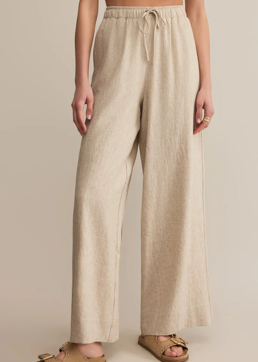Beige linen pants worn by a person on a beige background