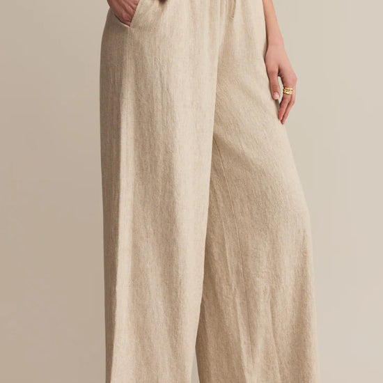 Beige linen pants worn by a person on a beige background