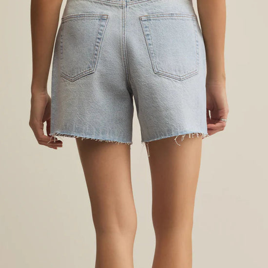 Light blue denim shorts worn by a person on a beige background