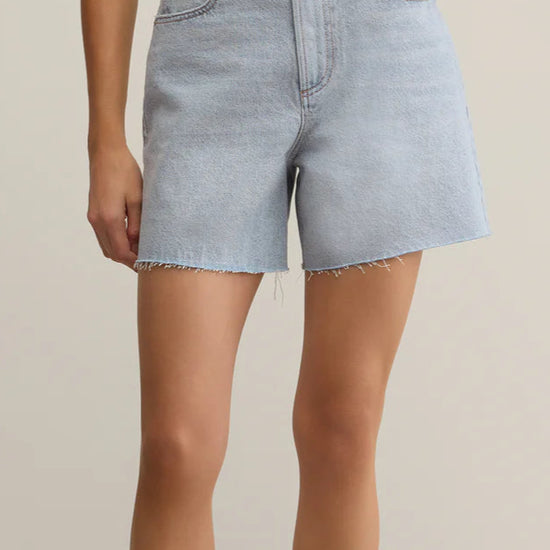 Light blue denim shorts worn by a person on a beige background