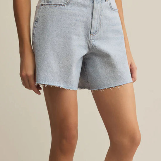 Light blue denim shorts worn by a person on a beige background