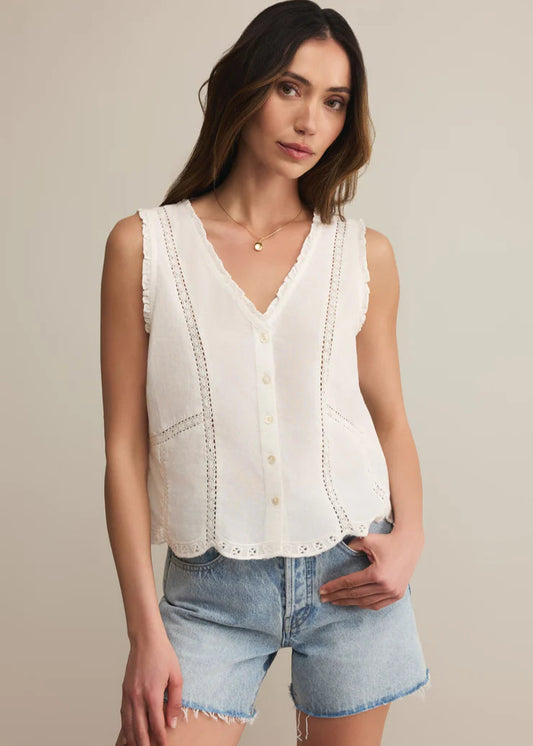 Woman wearing a white sleeveless top and denim shorts on a beige background
