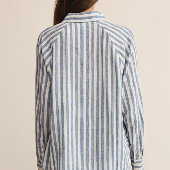 Person wearing a striped shirt from behind on a beige background