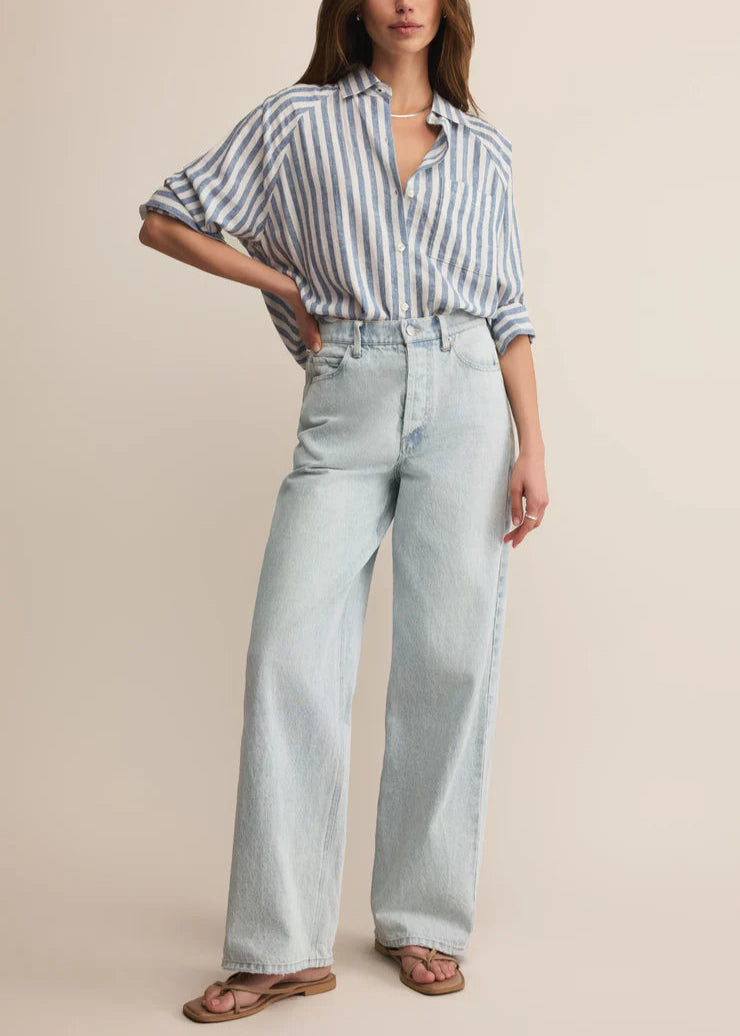 Woman wearing a striped shirt and light blue jeans on a beige background