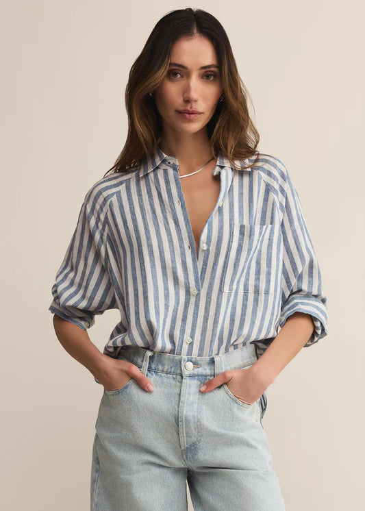 Woman wearing a striped shirt and jeans against a beige background