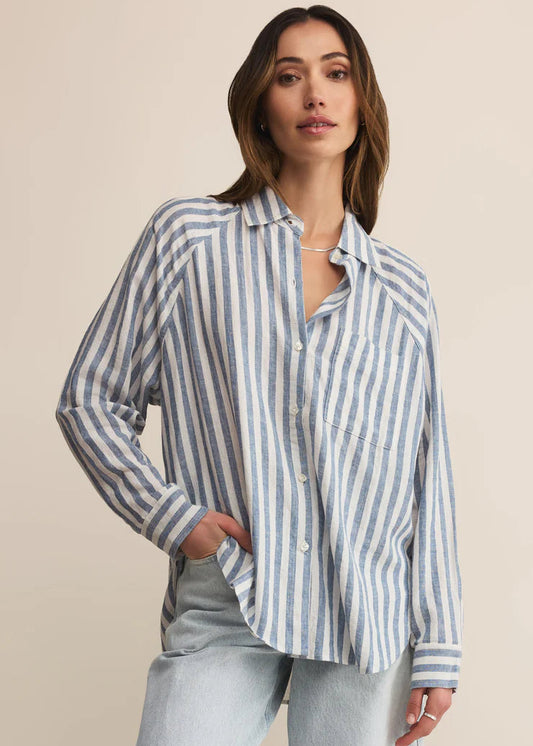 Woman wearing a striped shirt and light jeans against a beige background